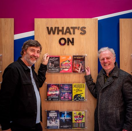 Two people standing in front of the Whats on leaflet racks in Box Office