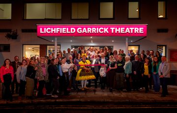 Photo of a large group of Trustees, Garrick Members, Garrick Staff, Councillors and Panto Dame, Sam Rabone, cutting the ribbon opening the newly refurbished front of house