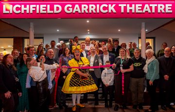 Photo of a large group of Trustees, Garrick Members, Garrick Staff, Councillors and Panto Dame, Sam Rabone, cutting the ribbon opening the newly refurbished front of house