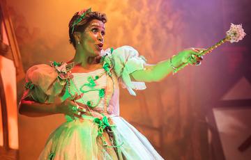 Fairy standing on stage with her wand pointing to the audience.